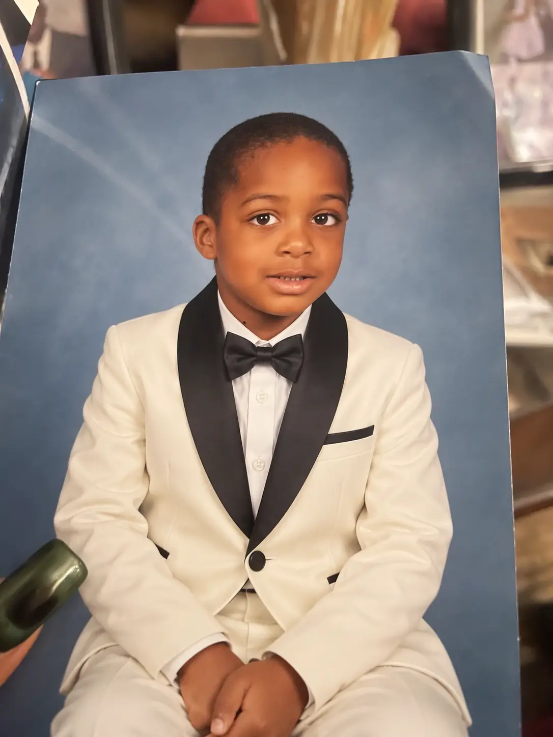 Edited portrait of the same child wearing an ivory tuxedo while the pose and background remain similar